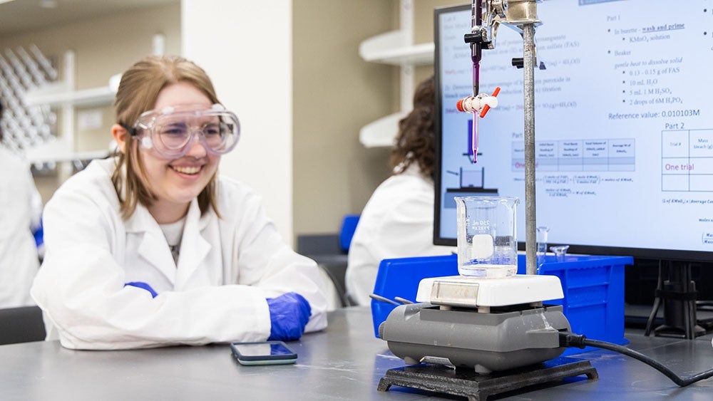 A student measures liquids in a chemistry lab. 